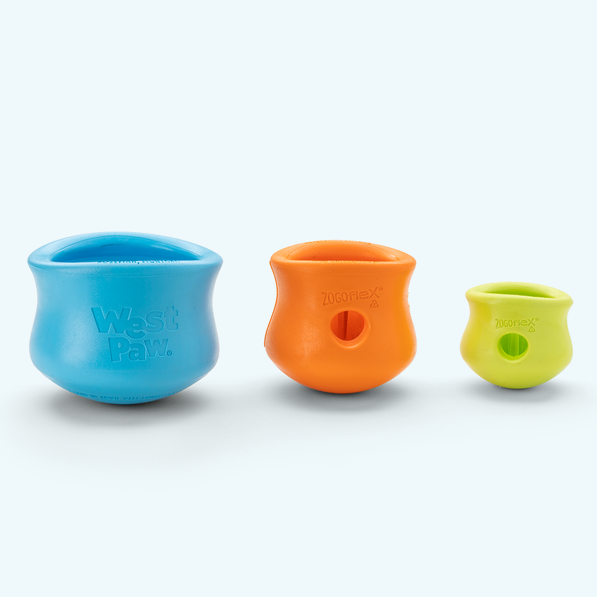 West Paw Toppl toys in aqua blue, tangerine and granny smith across three sizes